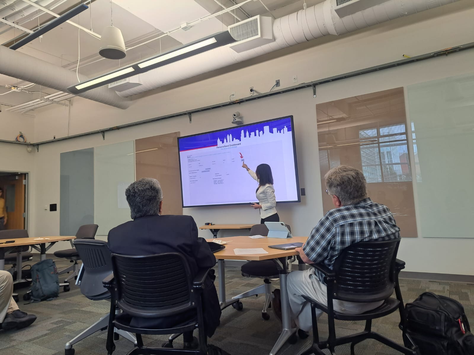Researcher presenting to audience in a conference room with large display screen